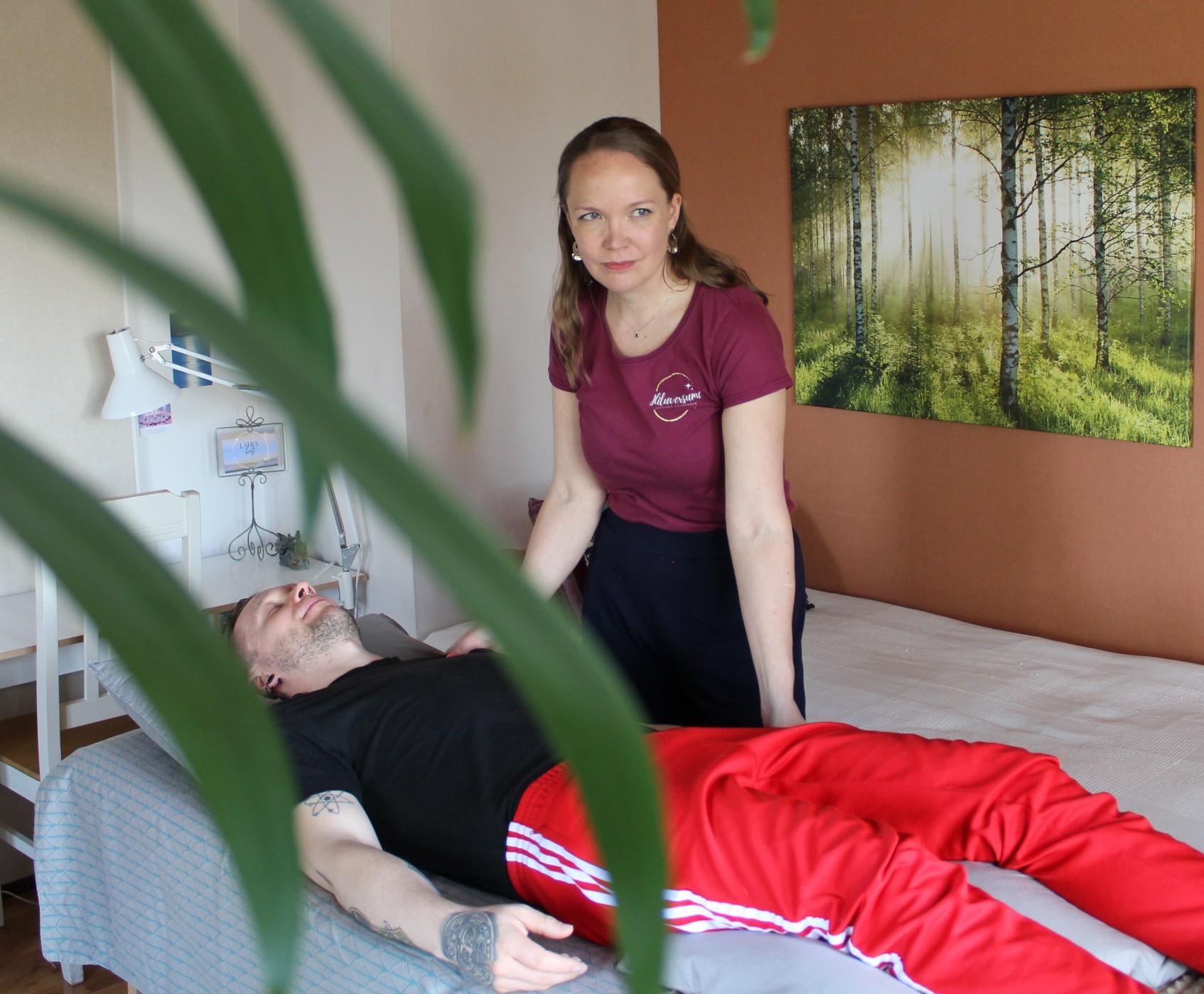 Mies makaa selällään hoitopöydällä, energiahoitaja hoitaa häntä käsin koskettamalla.